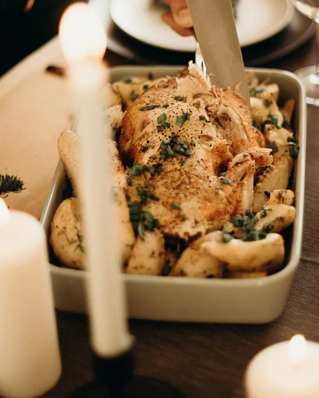 Pollo asado recién salido del horno en una mesa puesta para cenar